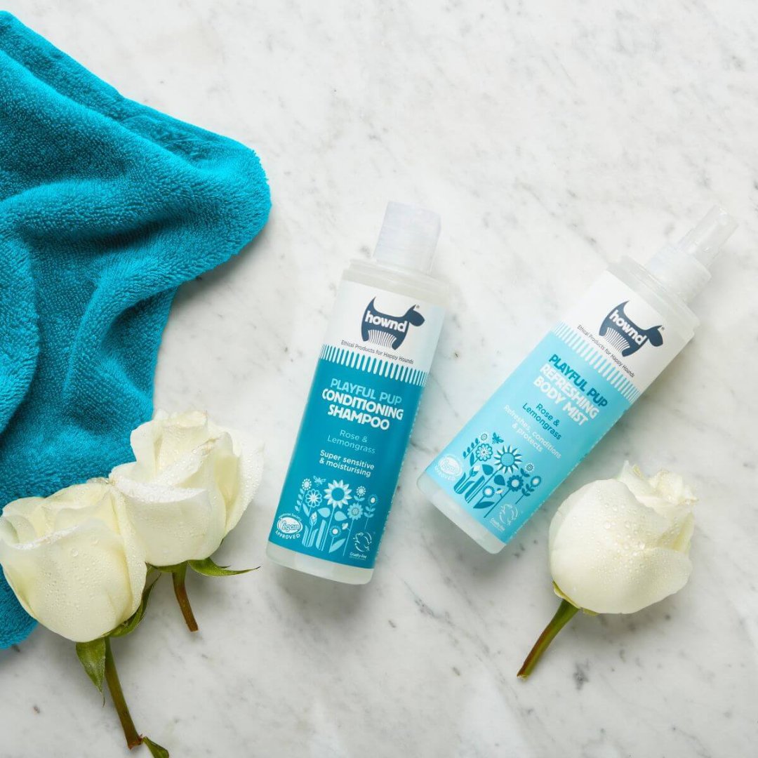 Playful Pup Body Mist! This specially formulated mist contains rose, lemongrass, and orange essential oils that release a lively and long-lasting fragrance Full.Hownd Playful Pup Body Mist - A bottle of mist spray surrounded by playful puppies.
